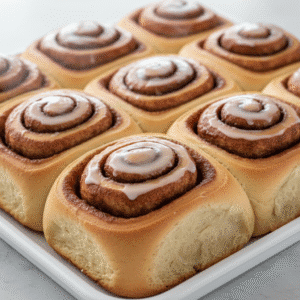 Cinnamon Rolls dorados y esponjosos sobre una mesa de madera, preparados con Mambo de Cecotec.